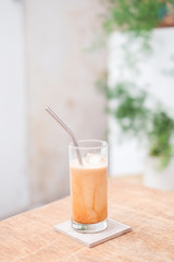 lce coffee (latte) in clear glass on wooden table for background or texture - relex concept.