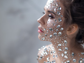Fantastic fashion portrait of a young beautiful woman with transparent crystals on her face and...