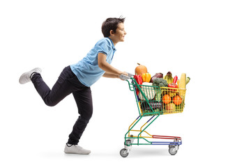 Boy running and pushing a little shopping cart with fruits and vegetables © Ljupco Smokovski