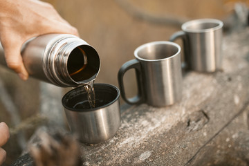 Man Pouring Hot Drink From Thermos Into Cups Outdoors