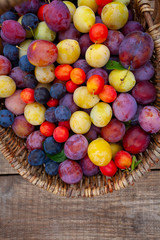 variety of plums on wooden surface