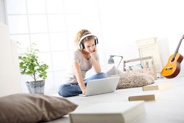 Fototapeta na wymiar young woman sitting in living room studying music with headphones and computer, stay at home concept