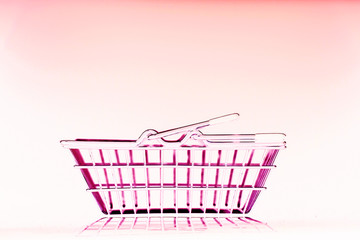 metal shopping basket on a pink background with reflection