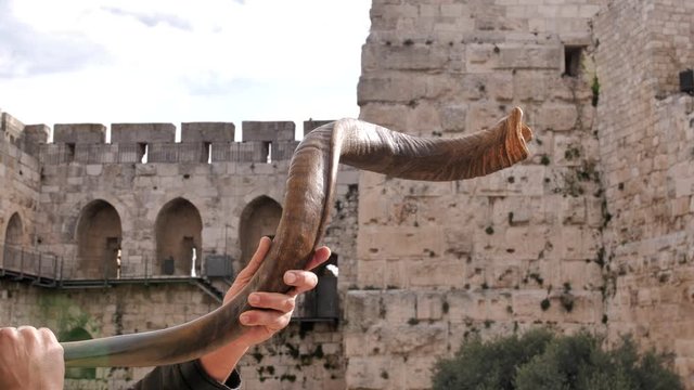 Jewish men blowing shofar in Jerusalem. Israel. The ancient walls of the old town, the City of David is on the background.