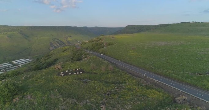 Aerial shot above Golan Heights and Taiberia in North of Israel. Car driving at road lane at Open fields with green landscapes and mountains above Galilee sea or Kinnert at Jordan valley 