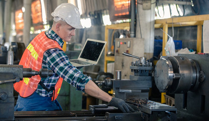 Fototapeta na wymiar man Lathe worker in production plant drilling at machine on the factory. Industrial engineer worker holding laptop Inspect workpieces