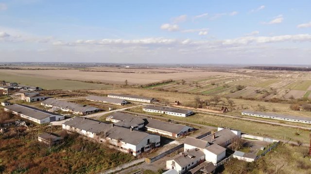 Bird's eye view of abandoned stables of a bankrupt collective farm. Aerial drone 4k, zoom in with pan