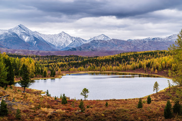 View of the Kidelu Lake and the snow-capped peaks of the Kurai ridge on the horizon. Autumn mountain landscape. Ulagansky District, Altai Republic, Russia