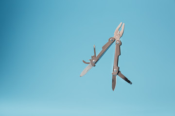 The multitool multi-function tool hovers on a blue background. The concept of an expanded...