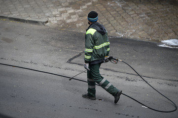 Public janitor deep cleaning the sidewalk with high pressure disinfectant solution in times of corona virus pandemic in a lockdown Bucharest, Romania