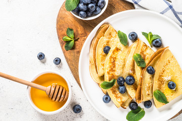 Crepes with blueberries at white table.
