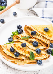 Crepes with blueberries at white table.