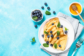 Crepes with blueberries at blue table.