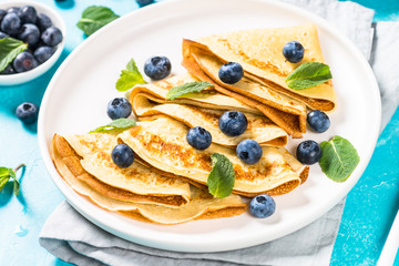 Crepes with blueberries at blue table.