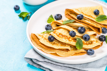 Crepes with blueberries at blue table.