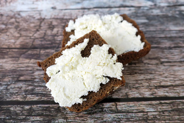 Ricotta on brown bread on wooden background