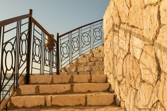 upstairs steps with metal railings and limestone wall. Limestone texture on the stairs