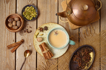 Masala chai tea traditional indian drink  with milk and spices on wooden background. Top view from above - obrazy, fototapety, plakaty