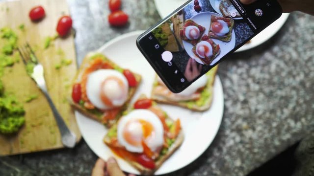 Taking Photos Of Healthy Avocado salmon Bruschetta with poached egg and tomato. Mobile Food Photography Concept.