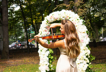 Beautiful young girl plays the violin. Girl with long hair plays the violin