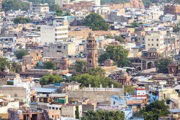Fototapeta na wymiar Stunning aerial view of the Jodhpur Blue City with the Clock Tower (Ghanta Ghar) and people walking in the Sardar Market. Jodhpur is a city in the Thar Desert of the northwest India.
