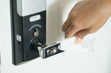Naklejka premium Close up hand cleaning desinfected metallic door handle door knob with the paper tissue against the virus