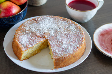 Freshly baked apple pie with powdered sugar on table