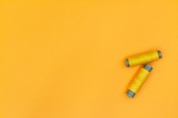 Yellow spool of thread on a yellow background. The concept of needlework, sewing.