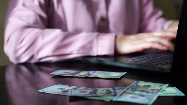Cash money falling on table of business woman working online
