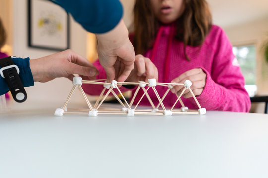Closeup of children building a pyramid out of toothpicks and marshmallows for a STEM project