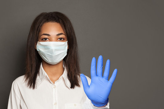 Woman Doctor Or Scientist In A Medical Face Mask Showing Stop Pandemic Gesture. Black Woman In Safety Mask And Medical Gloves