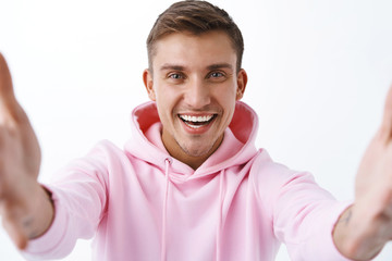 Close-up portrait of happy, friendly blond handsome man videochat friends during social-distansing covid19 pandemic, holding camera both hands, talking online via video call, laughing cheerful