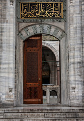 Mosque door with golden Arabic calligraphy above