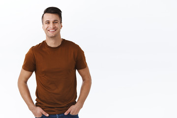 Better stay home. Portrait of handsome adult man with pleased happy smile, holding hands in pockets, natural casual emotion, looking camera friendly, standing white background