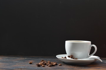 Café mocha cappuccino in a white cup next to coffee beans on a burned wooden tabletop with a black background