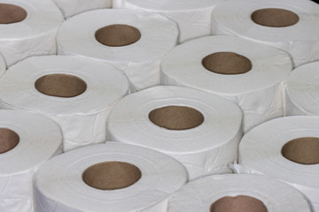 Layer of white toilet paper rolls seen from angle above filling frame