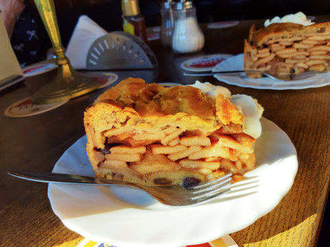 two slices of apple pie with whipped cream on a wooden table in a Dutch pub