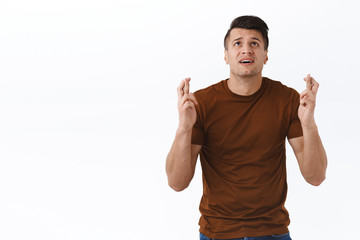 Fototapeta premium Hopeful nervous man begging god make his dream come true, look at sky with pleading desperate face, praying cross fingers good luck, supplicating as stuck in difficult situation, white background
