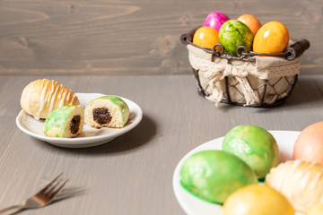 gefüllte bunte Ostereier aus Hefe mit Zuckerguss auf grauem Grund aus Holz für die Feiertage zum Kaffee