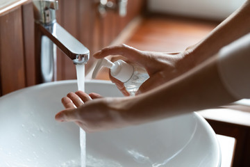Close up young woman put hands under water, cleaning with soap, individual hygienic routine. Cautious girl sanitizing hands regularly with antiseptic liquid, preventing coronavirus infection spread.
