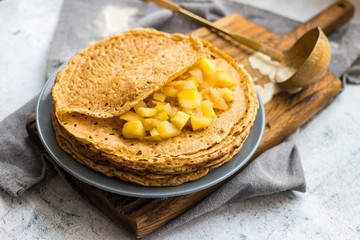Homemade golden crepes or thin pancakes stuffed with sweet cooked apples. Vegan dessert.