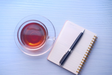 high angle view of tea, notepad and pen on white background.