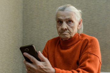 Elderly woman writes a message in a smartphone