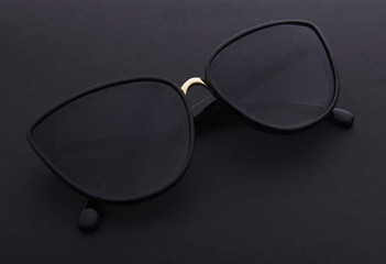 Black plastic stylish sunglasses on a black background.