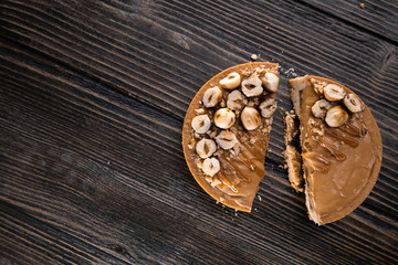 Delicious tart with caramel and hazelnuts  on the wooden background, halved. Top view, flat lay, natural light