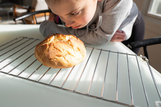 Young girl smelling freshly baked break on a kitchen counter