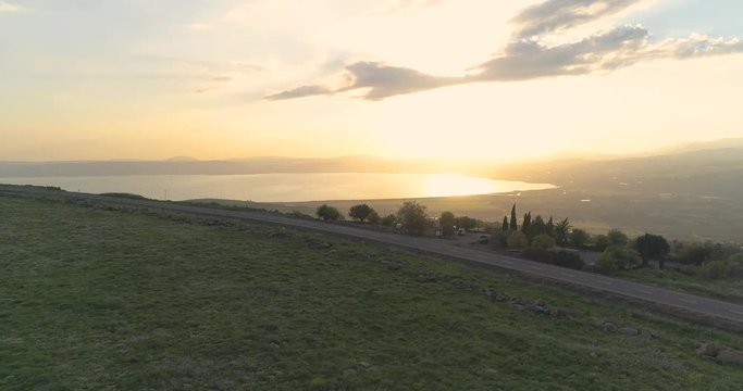Aerial shot at sunset above Golan Heights and Taiberia in North of Israel. Open fields with orange green landscapes and mountains above Galilee sea or Kinnert at Jordan valley 