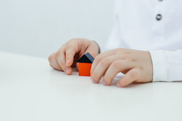 Concept of autism diagnosis and child development. A child stands a house made of colored wooden blocks of blocks. The control of behavior.