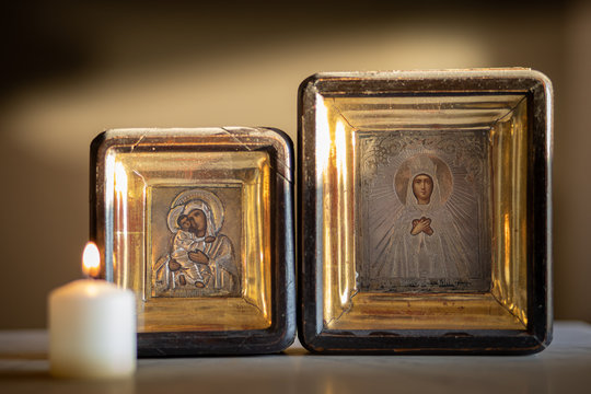 A candle burning in front of an icon of holy mother and child