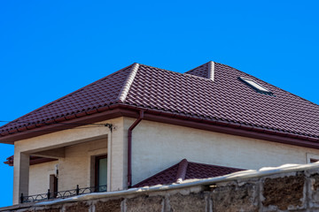Obraz premium Brown Tiled roof of the house with windows on a background of blue sky